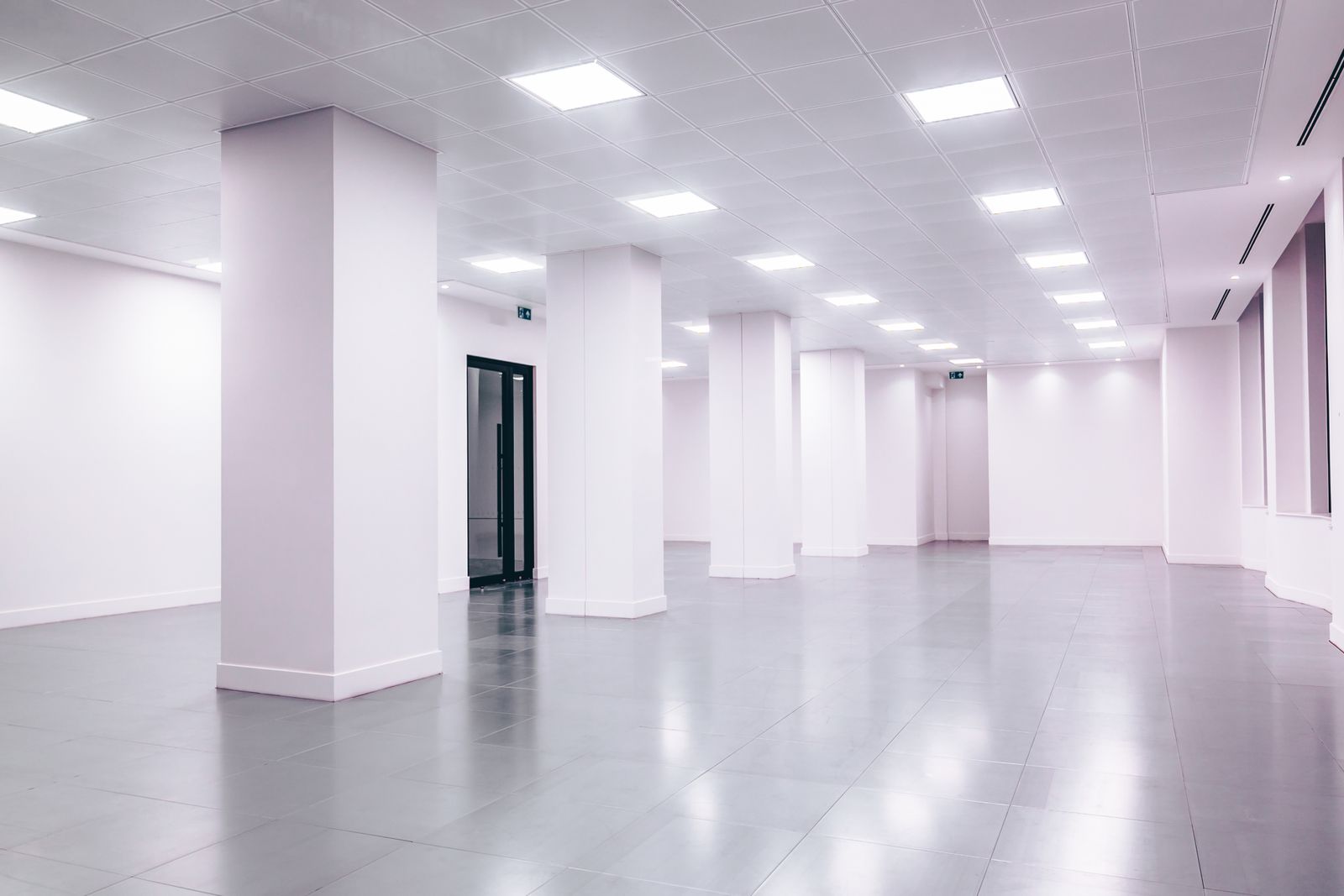 Wide-angle view of a modern minimalist white office space with clean lines and ample lighting.