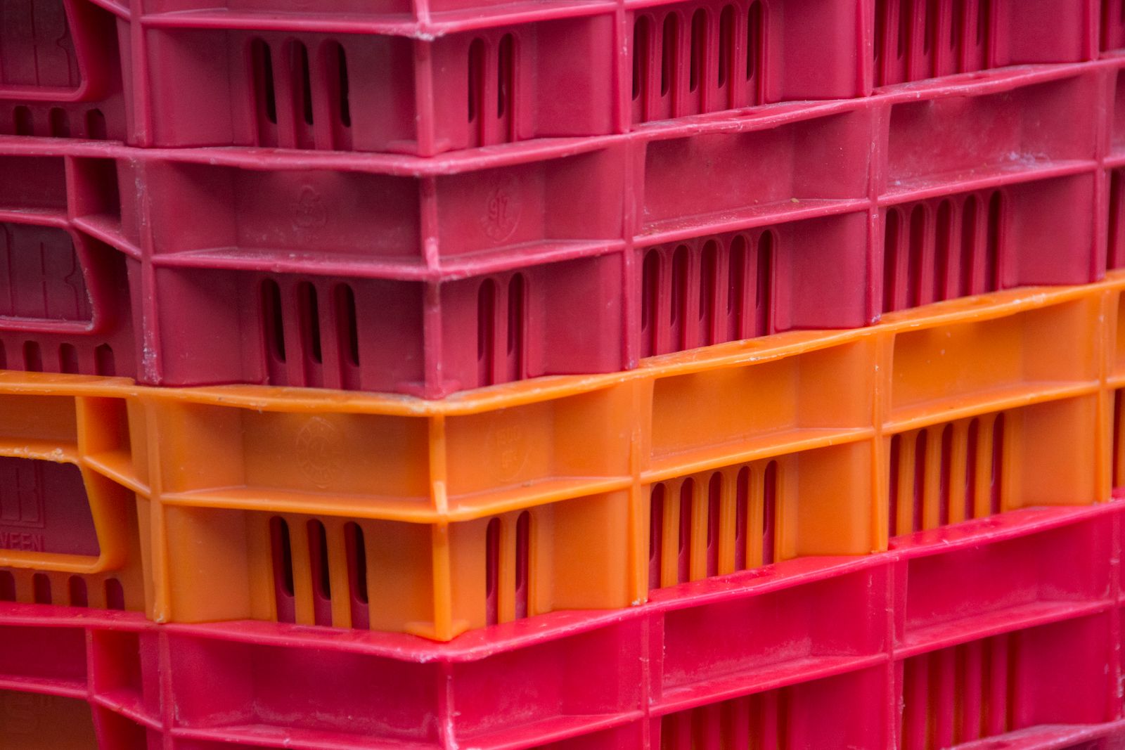 Close-up of red and orange plastic crates stacked in a colorful pile.