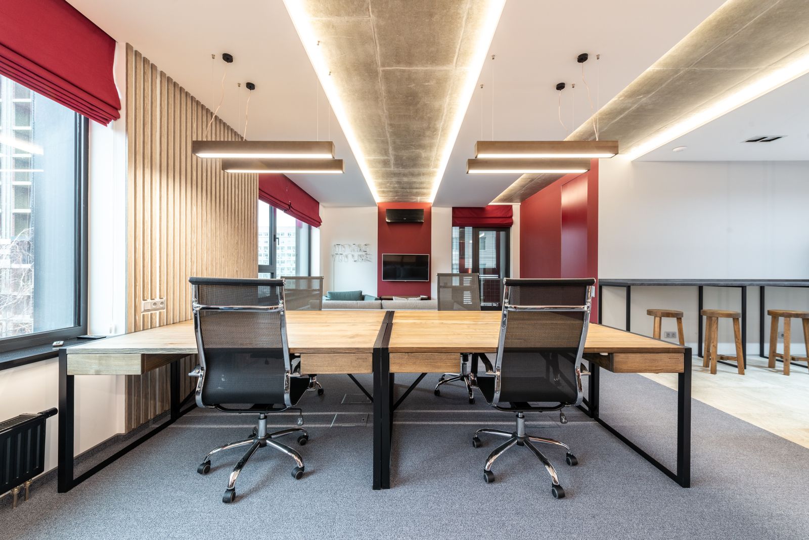 Interior of modern workplace with wooden table and chairs near window with jalousie under lamps